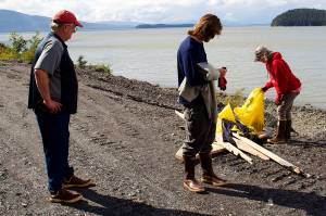 Hal Kulm (left), Luke Kulm (center) and Chanda Lawless place trash and lumber debris by the side of North Douglas Highway during a community shoreline cleanup. (Mark Sabbatini / Juneau Empire file)