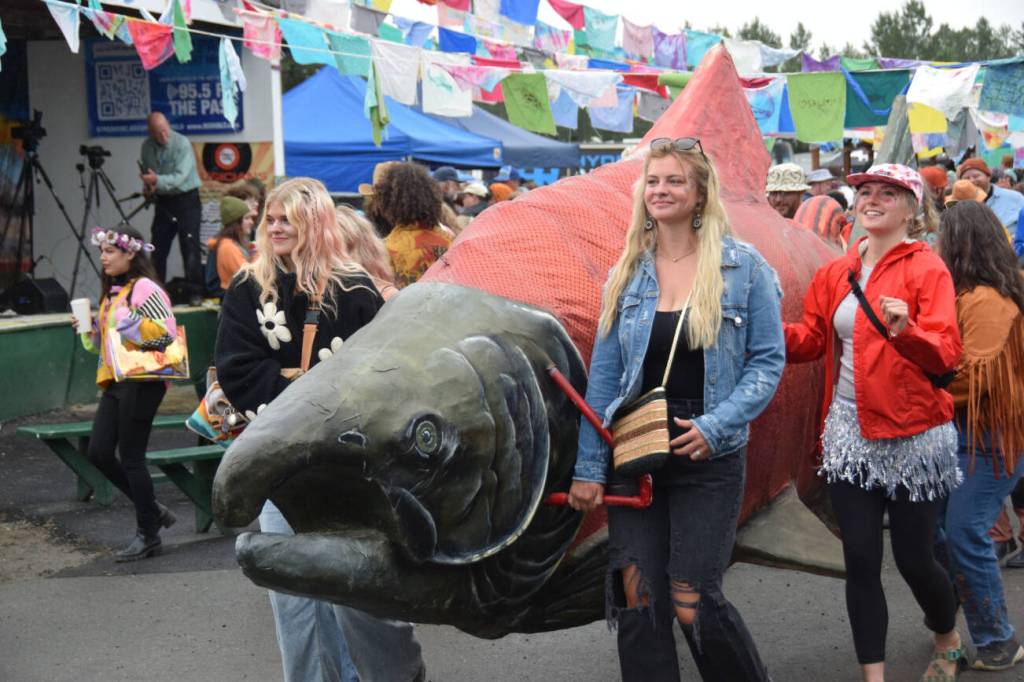 Salmonfest attendees accompany the Parkstrippers Marching Band through the Causeway, carrying a large salmon puppet, on Saturday, Aug. 2, 2025, at the Kenai Peninsula Fairgrounds in Ninilchik, Alaska. (Delcenia Cosman/Homer News)