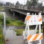 A sign warning of flood risk is posted by Brotherhood Bridge on Aug. 11, 2025. (Chloe Anderson for the Juneau Empire)