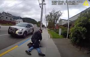 Former Juneau Police Department officer Brandon LeBlanc kneels beside man after violent arrest on July 30, as seen in police body cam footage. (Juneau Police Department screenshot)