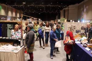 Shoppers and vendors mingle along rows of booths in the mall ballroom at Centennial Hall during the Juneau Public Market last year, which returns this year starting Friday, Nov. 28. (Mark Sabbatini / Juneau Empire file photo)