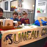 Middle schoolers Juniper Thompson, Tristan Roberts and Seaver Merrell fundraise for their schools Spring Odyssey camping trip at the Juneau Public Market on Friday, Nov. 28. (Mari Kanagy /Juneau Empire)