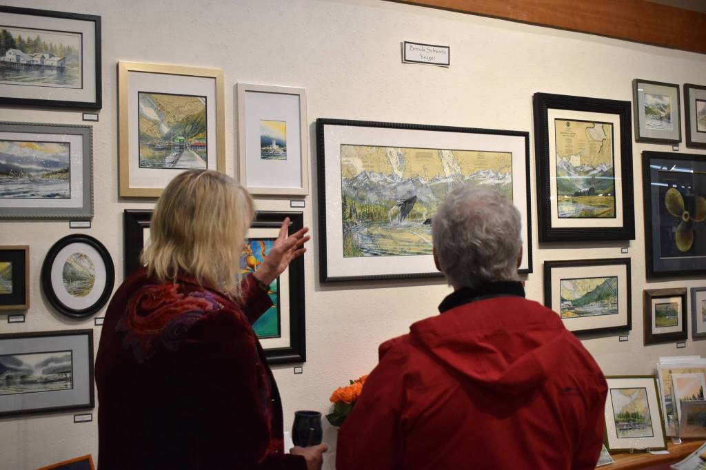 Brenda Schwartz-Yeager gestures to her artwork on display at Annie Kaills Gallery Gifts and Framing during the 2025 Gallery Walk on Friday, Dec. 5. (Mari Kanagy / Juneau Empire)