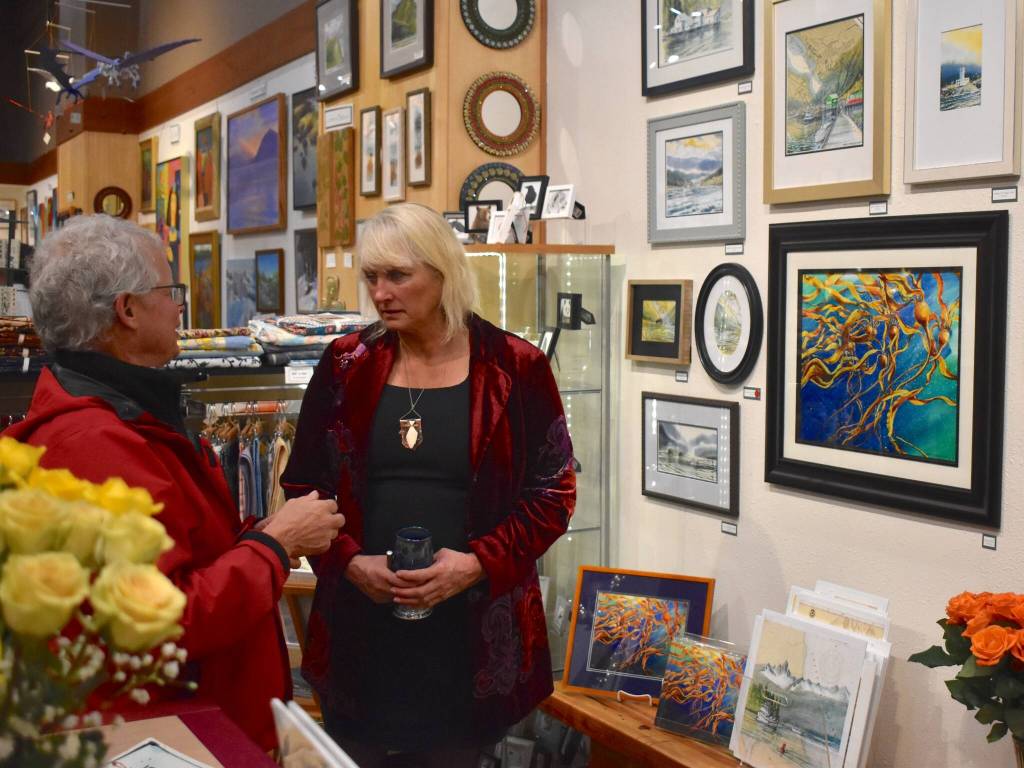 Brenda Schwartz-Yeager talks with a Gallery Walk attendee in front of her show at Annie Kaills Gallery Gifts and Framing on Friday, Dec. 5. (Mari Kanagy / Juneau Empire)