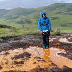 Patrick Sullivan stands by an acid seep on July 15,2023. Sullivan is part of a team of scientists who tested water quality in Kobuk Valley National Parks Salmon River and its tributaries, where permafrost thaw has caused acid rock drainage. The process is releasing metals that have turned the waters a rusty color. A chapter in the 2025 Arctic Report Card described rusting rivers phenomenon. (Photo by Roman Dial/Alaska Pacific University)