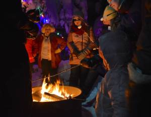Juneauites warm their hands and toast marshmallows around the fire at the “Light the Night" event on winter solstice, on Dec. 21, 2025. (Mari Kanagy / Juneau Empire)