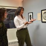 Alex Bookless stands as Rachel Levy talks about her work, Afterlife, part of their exhibition on display at the Juneau Arts and Culture Center. (Mari Kanagy/Juneau Empire)