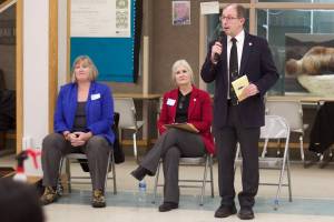 Juneau state Sen. Jesse Kiehl, standing, addresses a town hall audience Jan. 11 at Dzantiki Heeni Middle School as Juneau state Reps. Sarah Hannan, far left, and Andi Story wait their turn to discuss their priorities during the 2023 legislative session.(Mark Sabbatini / Juneau Empire file file)
