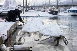 Salvage captain Trevin Carlile, left, and diver Phil Sellick at Melino’s Marine Service re-float a sunken boat in Harris harbor on Jan. 8, 2026. Record-breaking snow at the beginning of the month caused at least eight boats to sink in Harris, Douglas and Aurora harbors, resulting in oil spills. (Chloe Anderson for the Juneau Empire)