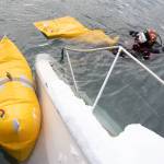 Melinos Marine Service diver Phil Sellick places flotation devices near the bow of a sunken boat in Harris Harbor on Jan. 8, 2026. (Chloe Anderson for the Juneau Empire)