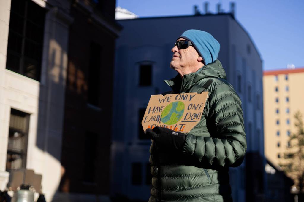 Jeff Wilson holds a sign reading We only have one Earth, dont burn it during a protest led by the Juneau-Douglas High School: Yadaa.at Kalé chapter of Alaska Youth for Environmental Action outside the Alaska State Capitol on Saturday, Jan. 24, 2026. (Chloe Anderson / Juneau Empire)