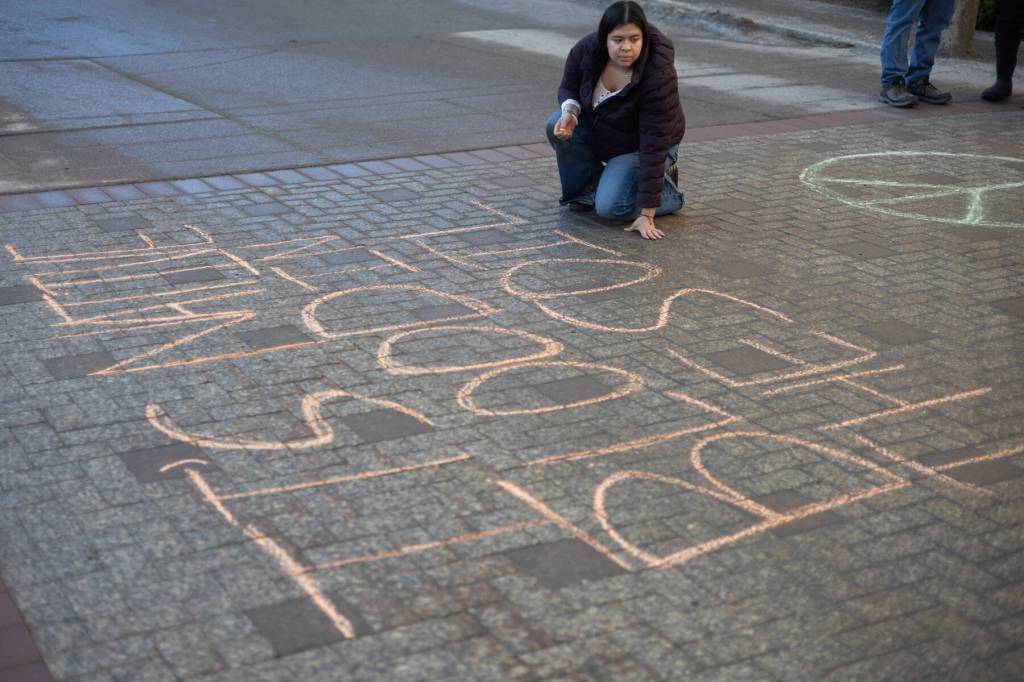 Macelle Joseph, a member of the Juneau-Douglas High School: Yadaa.at Kalé chapter of Alaska Youth for Environmental Action, writes Its Native blood in the soil, not your oil outside the Alaska State Capitol building on Jan. 24, 2026. Dozens of Juneauites participated in the student-led protest against the LNG pipeline. (Chloe Anderson / Juneau Empire)