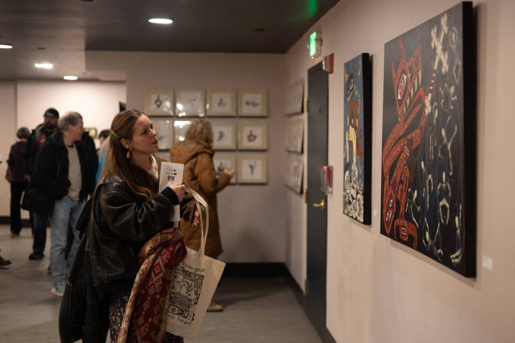 Tsimshian artist Erin Haldane examines other artists work on Jan. 24, 2026. Haldane, who works primarily in printmaking, watercolor and oil painting, has several collages and prints on display at Aan Hít in downtown Juneau through the exhibition Gestures of Our Rebel Bodies. (Chloe Anderson/Juneau Empire)