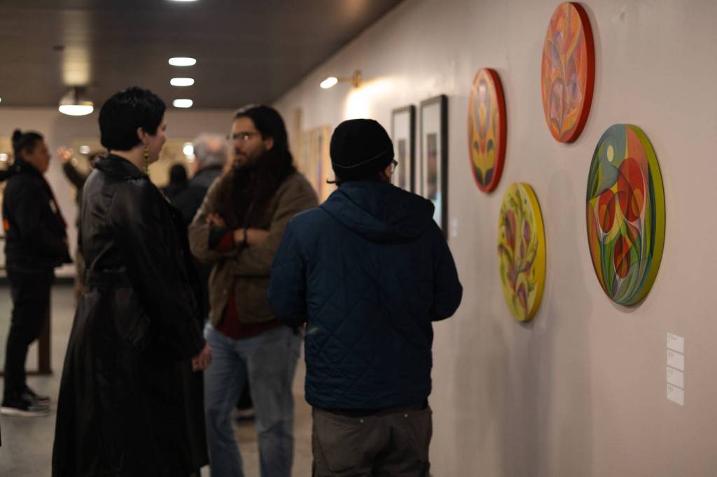 Exhibition attendees admire paintings by Tlingit artist Ursula Hudson during the opening night of Gestures of Our Rebel Bodies at Aan Hít on Jan. 24, 2026. (Chloe Anderson/Juneau Empire)