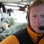 Martin Stuefer pauses before taking off from Eagle, Alaska, during the 2011 Yukon Quest. Stacked behind him are seven sled dogs in burlap sacks. (Photo by Martin Stuefer)
