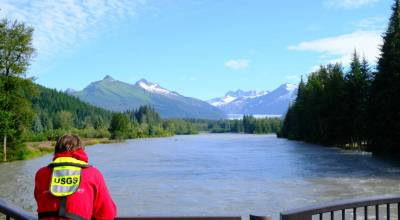 A U.S. Geological Survey worker views the flooding Mendenhall River from the Brotherhood Bridge following the glacial outburst event on Aug. 13, 2025. (Photo by Corinne Smith/Alaska Beacon)
