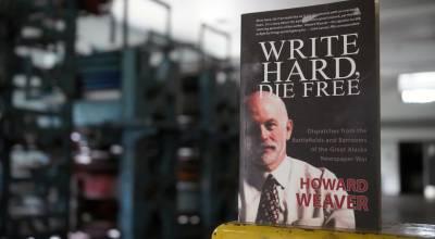 A copy of Howard Weavers memoir Write Hard, Die Free rests on an ink-splotched guard rail in front of the Peninsula Clarions defunct Goss Suburban printing press in Kenai, Alaska, on Thursday, June 20, 2024. (Jake Dye/Peninsula Clarion)